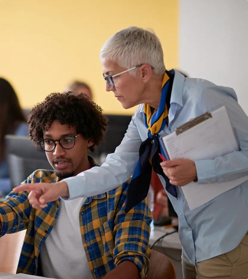 Two educators reviewing work together at a laptop